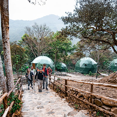 Guía de montaña liderando un grupo de turistas a su llegada a los domos Super Jungle Domes en la selva de Salkantay, Cusco.