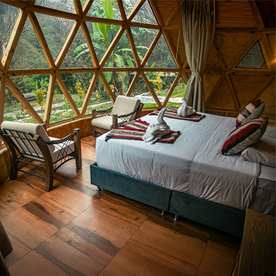 Vista detallada del interior de un domo de lujo en Sacred Jungle Lodge, mostrando camas matrimoniales premium y amplios ventanales con vista a la vegetación tropical de Santa Teresa.