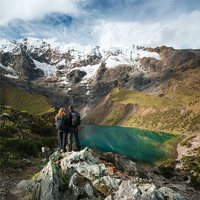 Pareja de turistas frente a la laguna turquesa Humantay y el nevado Salkantay en Cusco, Perú.