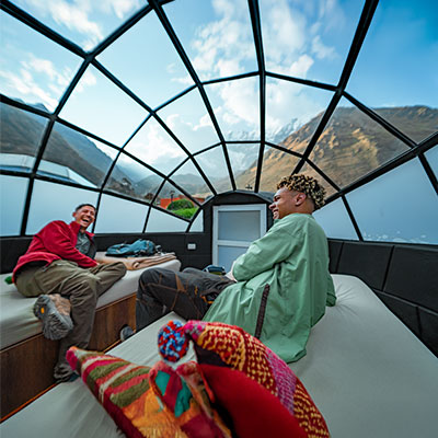 Turistas descansando dentro de los domos de cristal de Sky Camp con vistas panorámicas a las montañas nevadas de Soraypampa.
