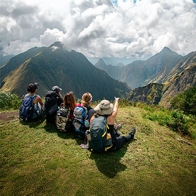 Grupo de excursionistas contemplando la ciudadela de Machu Picchu a lo lejos desde el sitio arqueológico de Llactapata.