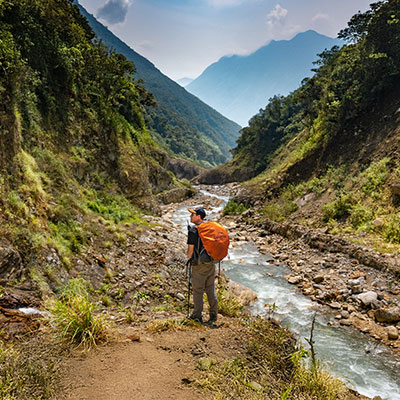 Turista caminando por el sendero tropical del valle de Santa Teresa hacia el campamento de Lucmabamba en el camino Salkantay.