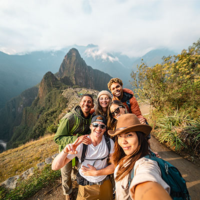 Grupo de viajeros tomándose un selfie desde el mirador de la Casa del Guardián con la ciudadela de Machu Picchu y el Huayna Picchu de fondo.
