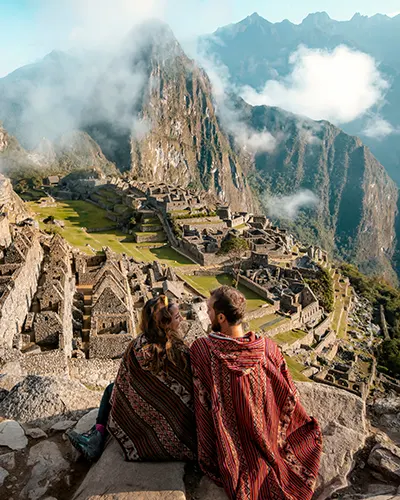 Una pareja de viajeros impresionados con la maravillosa vista de Machu Picchu