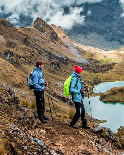 Dos turistas paseando por los maravillosos lagos y montañas de la ruta de Lares