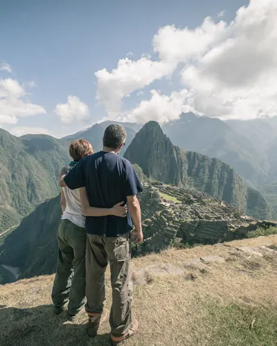 Pareja de turistas se abraza disfrutando de una impresionante vista de Machu Picchu